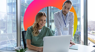 Two medical professionals review information on a laptop