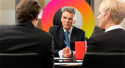 A lawyer talking to a male and female lawyer at a desk shi logo in background