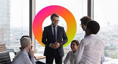 Group of employees huddled together around a male in a suit shi halo in background