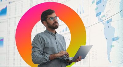 Man holding laptop looking at infographics on a large screen