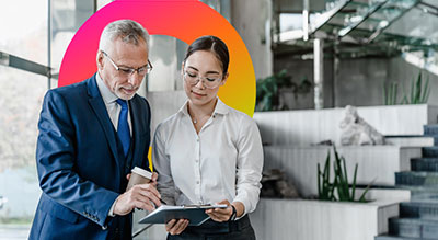 A person review a contract that another individual is signing on a clipboard