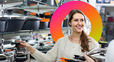 A woman happily holds a set of pots and pans, radiating joy with her smile.