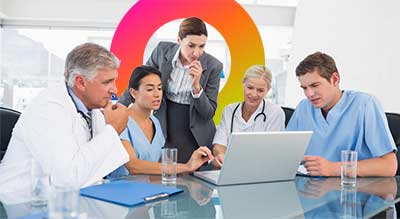 A group of medical professionals having a discussion around a table with a laptop