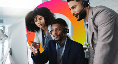 Three professionals in professional attire, collaborating around a computer in a well-lit office setting