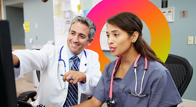 Two healthcare professionals discussing something in front of a computer