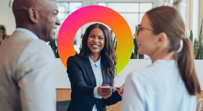 A professional woman in a suit confidently shakes hands with two individuals, symbolizing a successful business interaction.