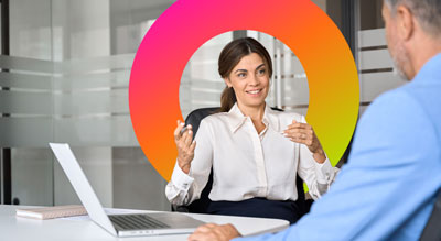 Two individuals engaged in a conversation while sitting at an office desk