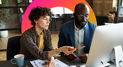 Two people in an office working on papers and a computer