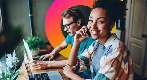 coworkers at a desk in front of laptops