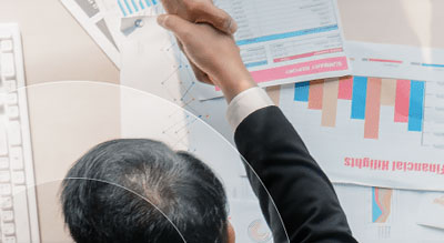 Top down view of a man shaking hands overs a table covered in spreadsheets