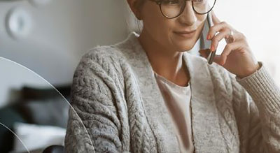 Woman uses cellphone while looking at laptop screen