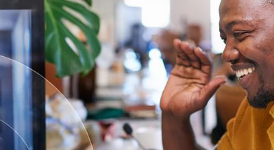 smiling man waving at a child through a webcam
