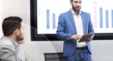 Man gives speech in an office meeting while holding a tablet