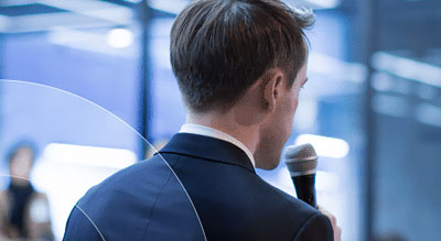 Man presenting with a microphone looking onto a crowd