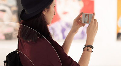 Woman at museum takes cellphone photo of artwork