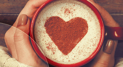 Close up of a coffee mug with a red heart design at the top of the liquid