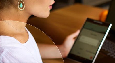 A person is focused on their laptop with a smartphone in a casual indoor setting