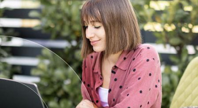 smiling woman uses laptop outside