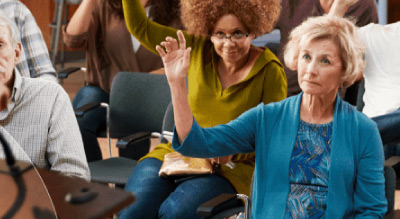 Caucausian and african american women raising her hand sitting down ina group of senior citizens