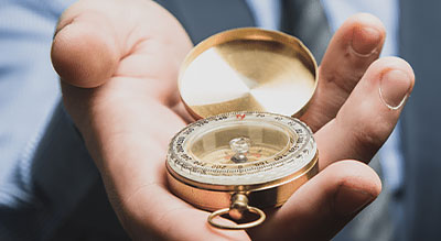 An outreaching hand holds a compass