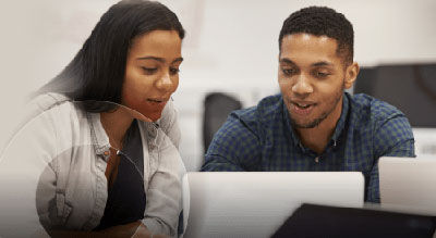 Two people review information on a laptop together