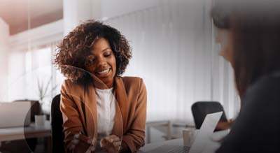 A smiling woman consults another person