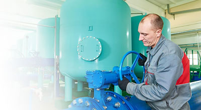 Mechanic cranks a valve on a large pipe
