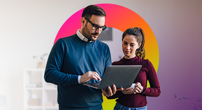 Two people talking to each other while one of them holds a laptop