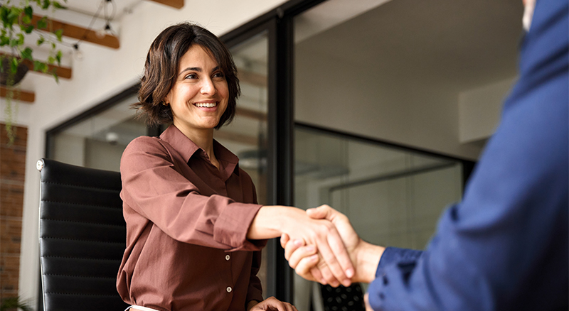 Two p;eople shaking hands in an office setting