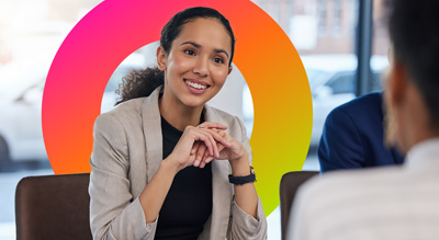 A smiling woman listens in a consultation with two other people