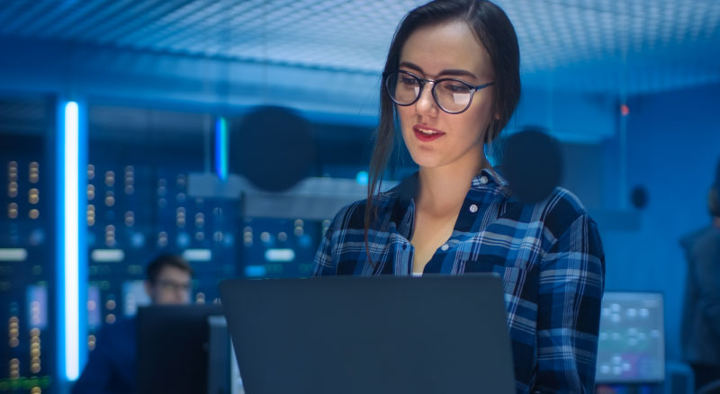 A person holding a laptop in a server room