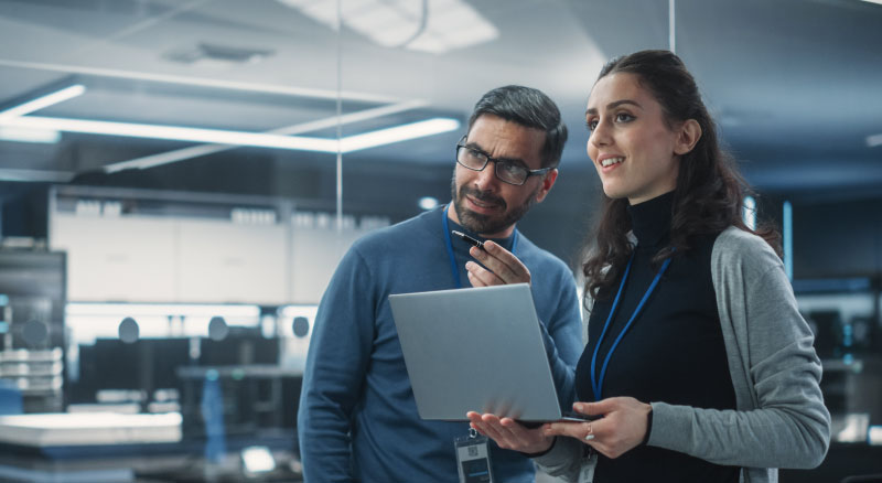 Three people working together in an office, using laptops and tablets