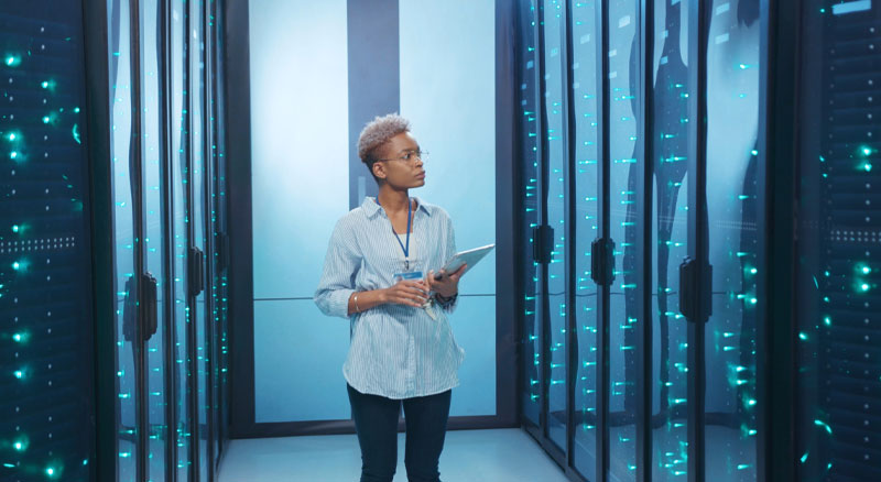 Administrator with tablet observing work operations in data center server room
