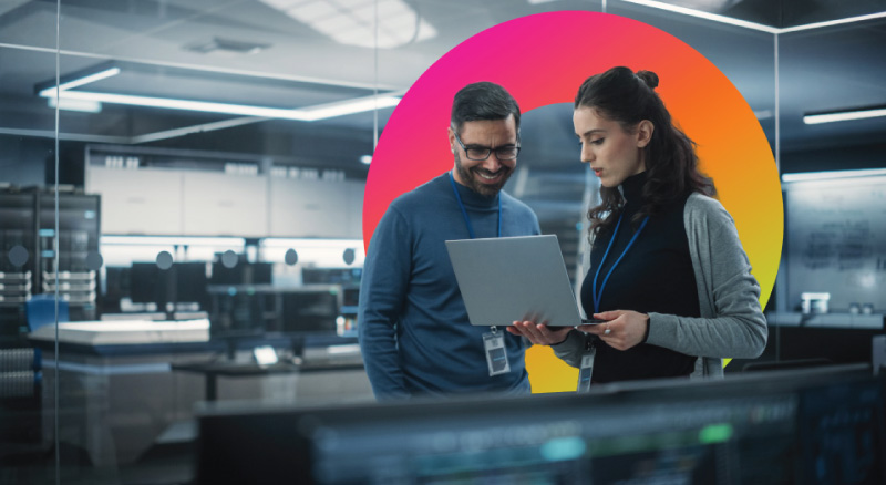 Two people in an office with glass walls look at a laptop together; colorful circular graphic decorates the background.