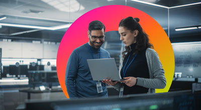 Two individuals in an office are looking at a laptop