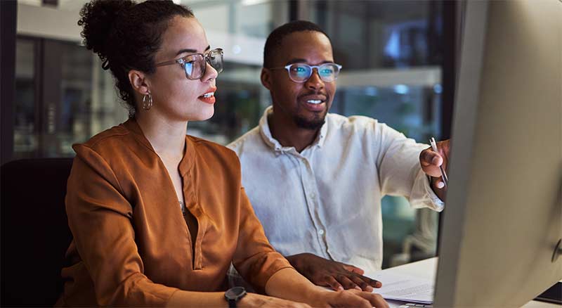 Image of a male and Female coworkers looking at a computer discussing data control and hybrid infrastructure