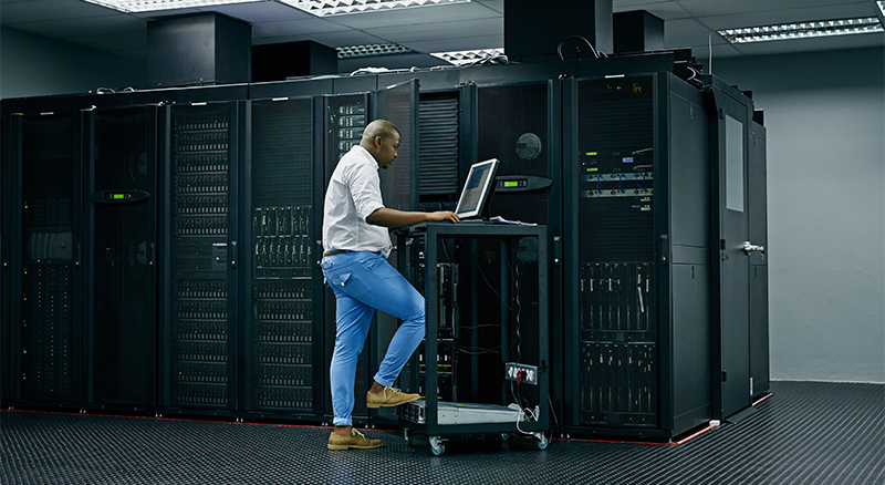 Person standing in a server room analyzing server equipment