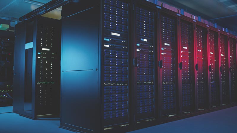 A row of server racks in a data center illuminated by blue and red lights
