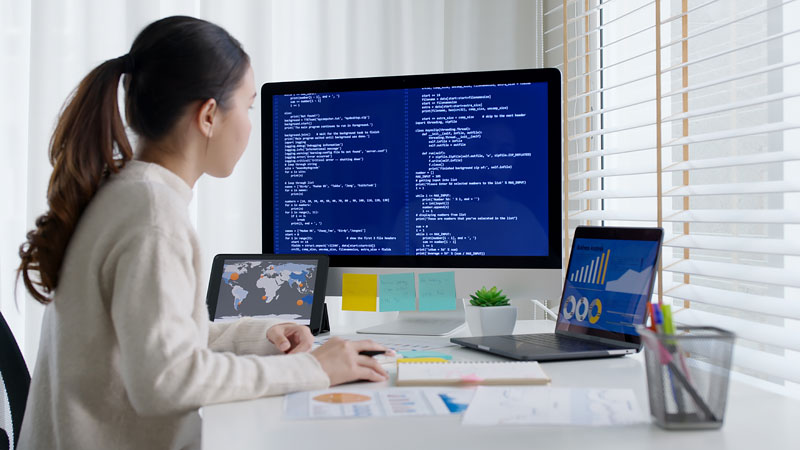 A woman review code while working on a computer