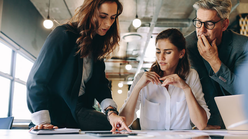 Two women and a man reviewing data together at a desk