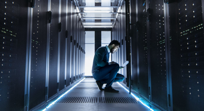 Employee working on a laptop in a server room