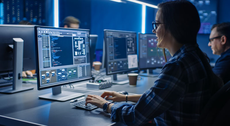 Girl working on two computer monitors in server room