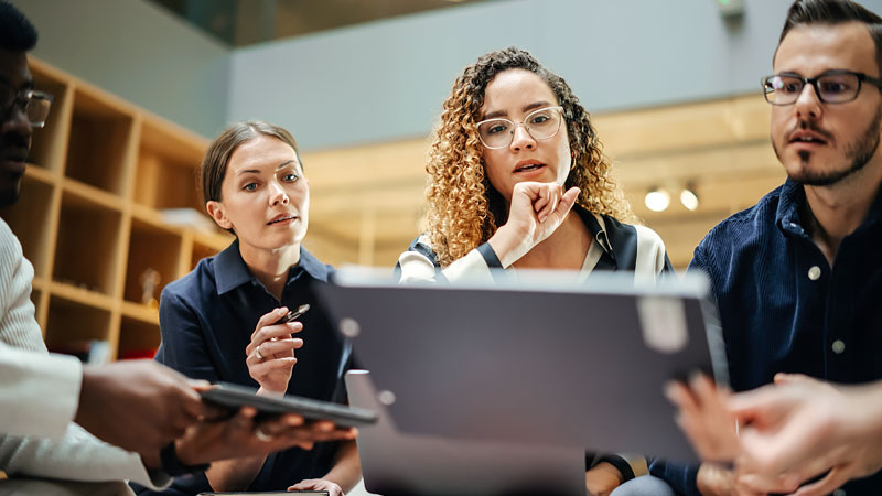 A diverse team actively analyze information on digital devices