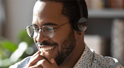 A person wearing headphones and glasses is seated in a home office setting