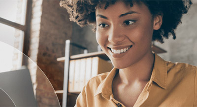 A personal smiles while sitting behind a laptop in a home office environment