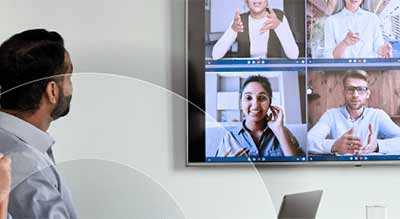 A person is viewing a video conference on a screen with four participants