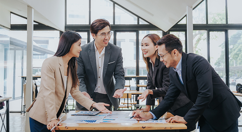 Four people in business attire having a meeting around a table in a modern office