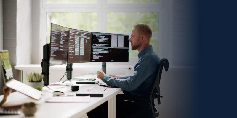 Person using three monitors in an office