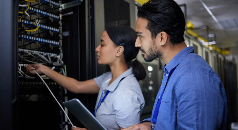 Two professionals examining a server rack in a data center