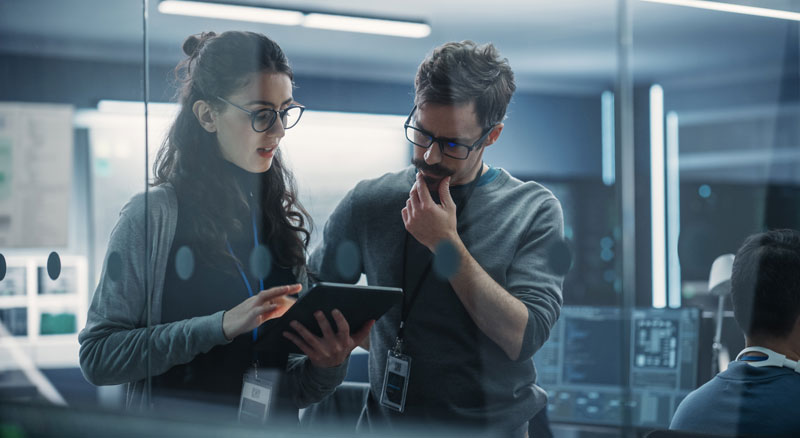 Two colleagues using a tablet to review business data in a bright office space